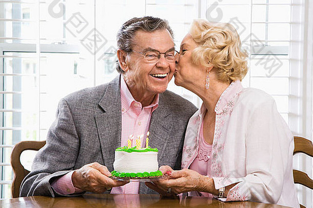 成熟的白人女人拿着生日蛋糕亲吻成熟的白人男人