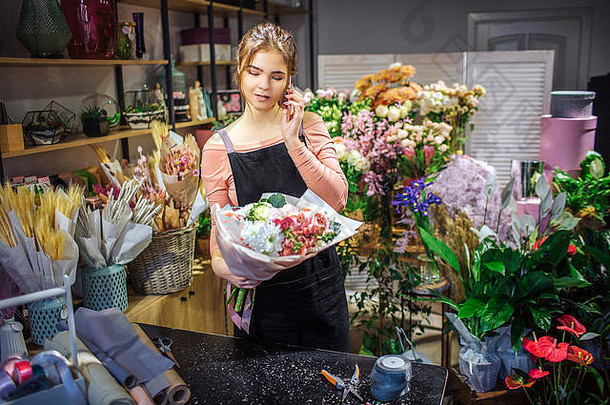 忙年轻的花店持有花束手说话电话年轻的女人站房间完整的花植物