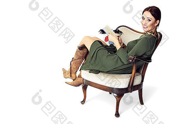 年轻的女人坐着椅子持有书