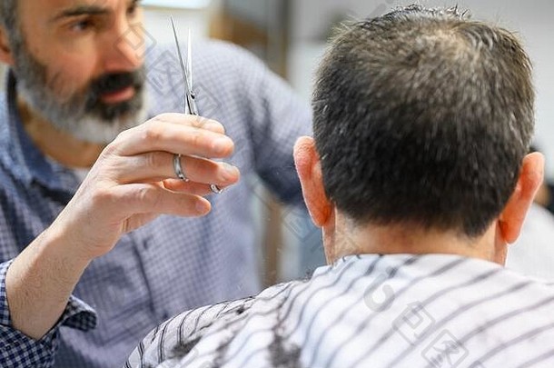 理发师在理发店修剪<strong>老人</strong>的头发。