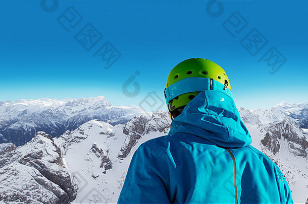 阳光明媚的日子里，年轻滑雪者的背部。阿尔卑斯山全景图