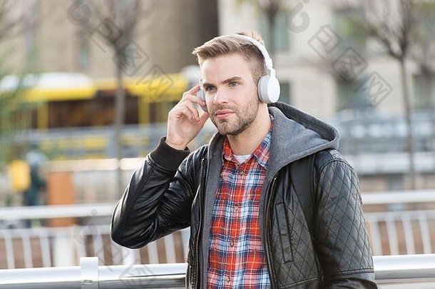 音乐、声音和技术。帅哥在户外戴耳机。没刮胡子的家伙在街上听音乐。新技术。高保真技术。现代音乐技术。现代生活。