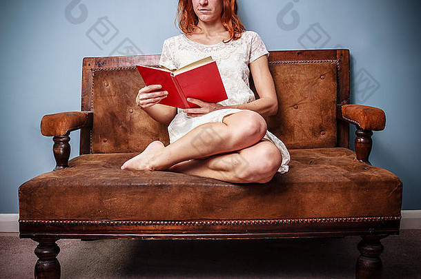 坐在沙发上读红皮书的年轻女子