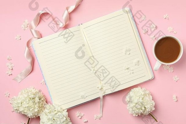 粉色背景上的笔记本、咖啡和绣球花