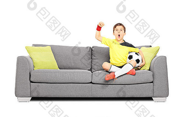 坐在沙发上拿着足球欢呼的孩子