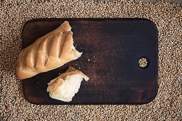 以麦粒为背景的厨房板上的碎面包