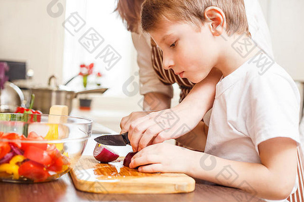小男孩和他的母亲在<strong>厨房</strong>里切菜做沙拉家庭烹饪背景