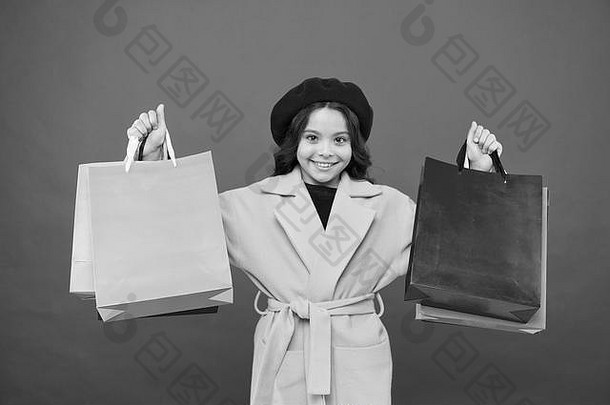 通过商店的春季大减价，让衣橱焕然一新。女孩可爱的孩子拿着购物袋红色背景。在生日假期享受折扣购物。时尚达人喜欢购物。沉迷于购物。