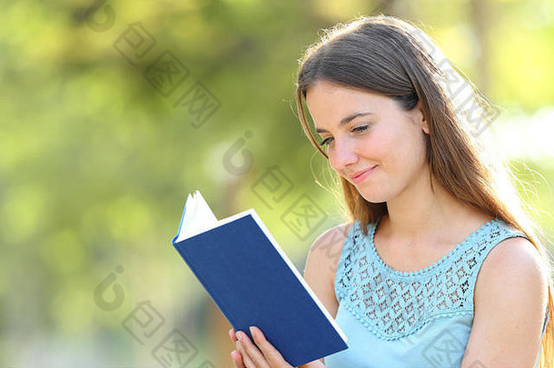 一个严肃的女人在公园里读一本绿色背景的空白纸质书