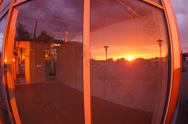 日落时的城市景观，通过广角鱼眼镜头和扭曲视图反映在一个空<strong>店铺</strong>的窗户上
