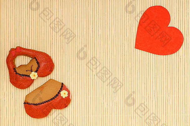 比基尼内衣形状姜饼饼干和红色心形爱情象征在竹垫上。情人节。