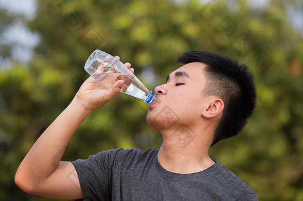 年轻的男人。少年喝水塑料瓶