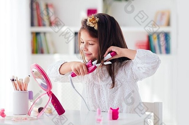 漂亮的年轻女孩，小孩用铁卷发器和玩具美容套装卷发