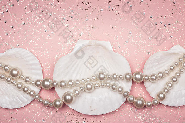 珍珠项链和贝壳，背景为亮粉色。美丽与时尚理念。