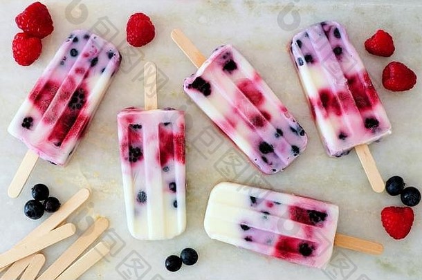 健康混合浆果酸奶冰棒，白色大理石背景，带水果