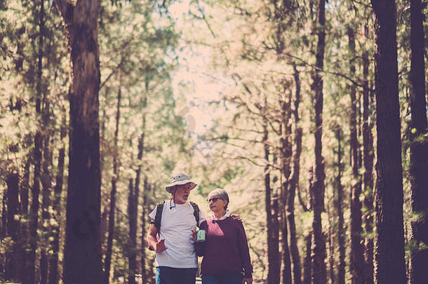 两位高加索人老年旅行者背着背包，在森林里自由漫步，享受自由探险的生活方式