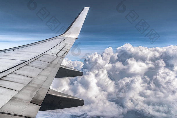 从飞机靠窗一侧的座位上可以看到壮观的云层。机翼及其所有组件均可见。云像棉花球一样蓬松。