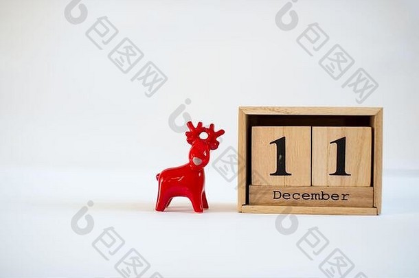 立方体木制日历，显示12月11日的日期，白色背景上有陶瓷驯鹿雕像。降临节日历，圣诞节背景