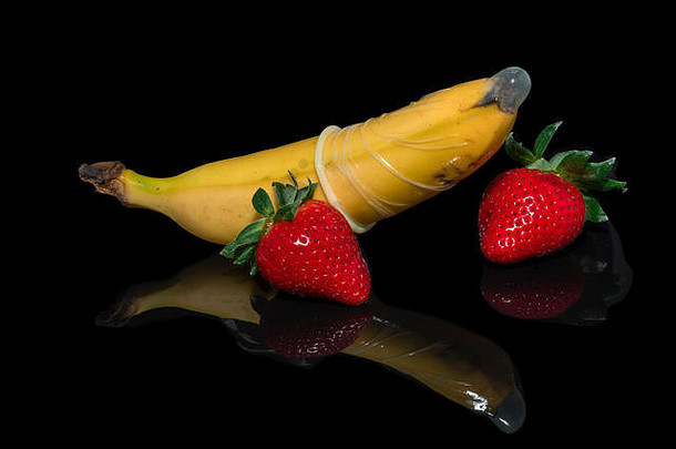 安全套中的香蕉，黑色背景上有两个草莓