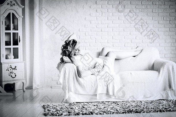 复古风格的黑白照片。躺在沙发上的快乐的年轻孕妇