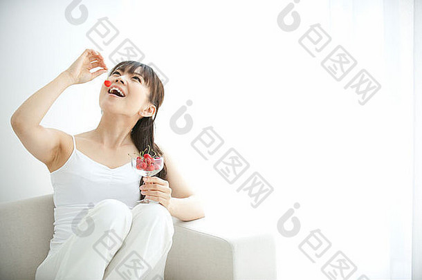 日本大阪县女人坐着沙发吃樱桃