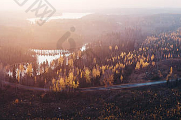 芬兰，日落时分，湖水倒映，道路空旷，秋色森林的全景图