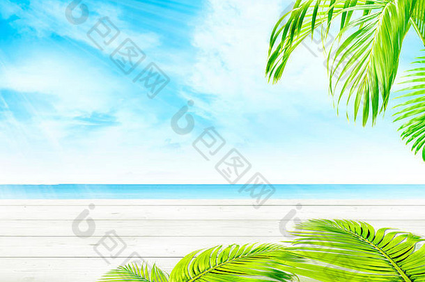 木制桌子和绿色棕榈枝，在蓝天背景下可以看到蓝色的海景