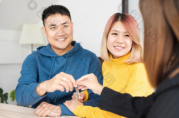 亚洲幸福夫妇在新家与面带笑容的房地产经纪人取得钥匙。购买新房地产
