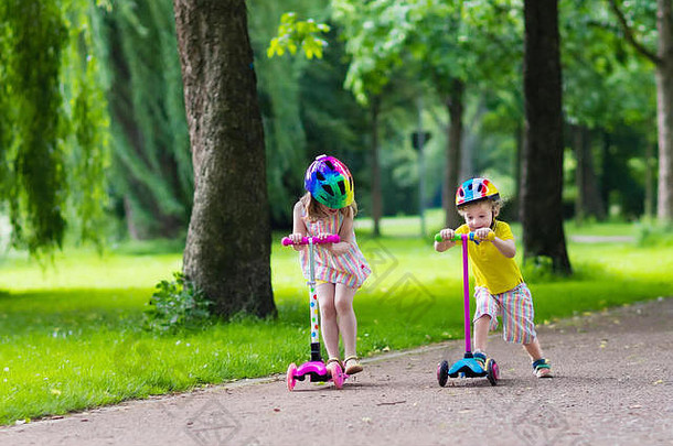 孩子学习骑踏板车城市公园阳光明媚的夏天一天可爱的学龄前儿童男孩安全头盔骑辊