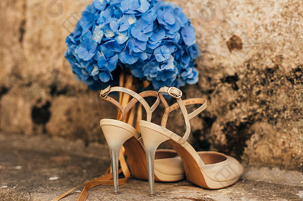 石头背景上新娘的结婚鞋和蓝色新娘花束