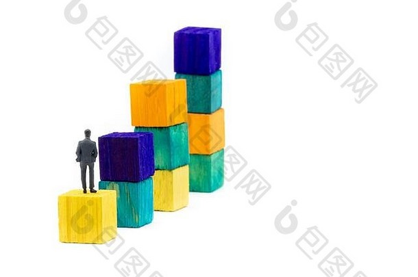 一个微型雕像，扮成一个商人，独自坐在一个木制的立方体上，仰望着五颜六色的堆积如山的商业图表，极简抽象概念i