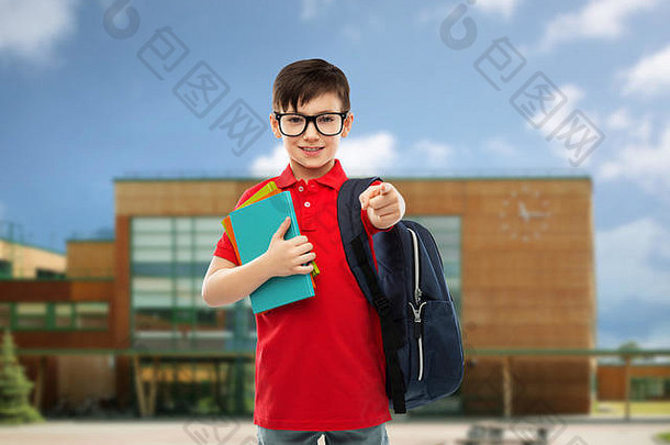 一个拿着书和书包在学校的男生