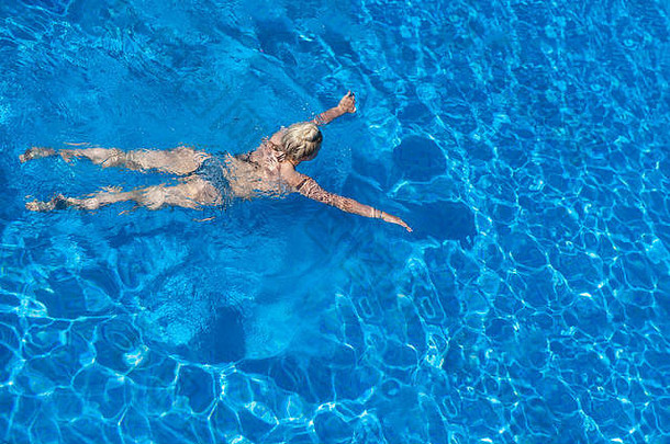 一个金发女孩在一个无限的游泳池里游泳