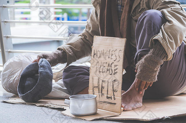 无家可归的一个戴着黑手套的不幸的无家可归者牵着手从人们那里得到<strong>零钱</strong>或帮助捐赠食物。