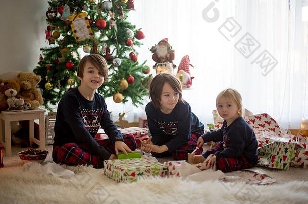 快乐的孩子们，孩子们，在圣诞节打开礼物，穿着睡衣