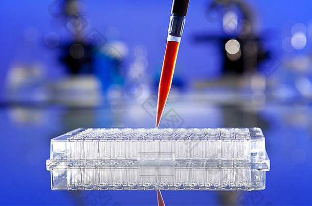 在实验室环境中，装有显微镜和其他设备的充满血样或红色液体的移液管和细胞托盘