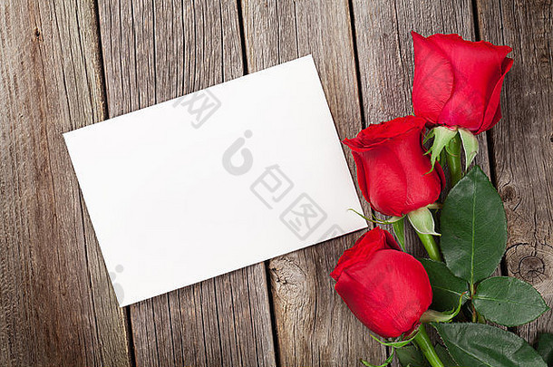 木桌上放着红<strong>玫瑰</strong>和情人节贺卡。具有空间的俯视图