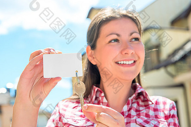 微笑的女孩展示联排别墅的钥匙，专注于钥匙