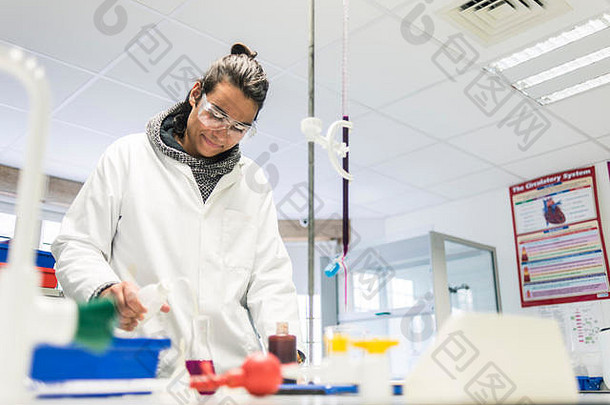 一名年轻的男生穿着白色实验服在剑桥大学的科学实验室工作