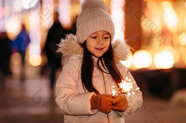 晚上街上挂着孟加拉灯的可爱的微笑小女孩