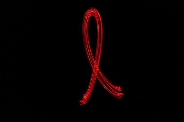 字母的光绘照片，由霓虹红色的仙女灯在黑色背景下绘制。长曝光摄影。