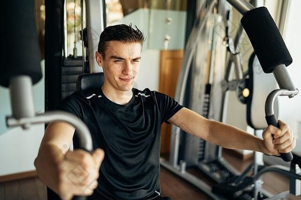 年轻人在家里的健身房里做健身操。努力训练，打造健美的夏季体型。家庭锻炼。重量下限