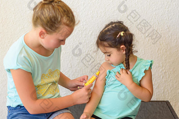 扮演医生的孩子们。医生在手臂上注射流感疫苗接种小女孩，健康医疗理念。