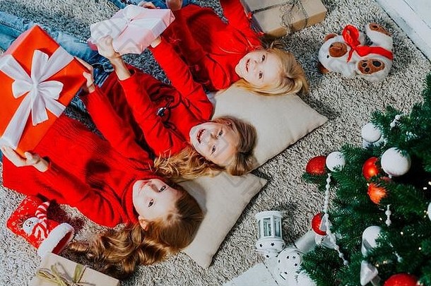 两个金发小女孩躺在圣诞树旁，准备新年礼物