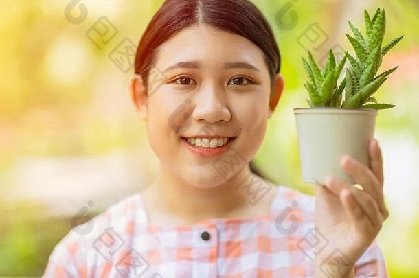 亚洲女孩少女微笑着把仙人掌壶用于拯救地球环境，并使用绿色植物产品实现良好的健康理念。