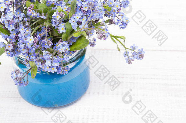 白色木质背景上的罐子里的蓝色小花
