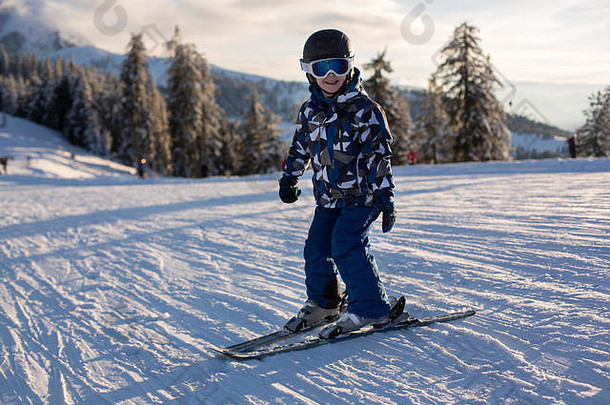 可爱的学龄前儿童，男孩，在奥地利阿尔卑斯山的日落上滑雪，风景优美