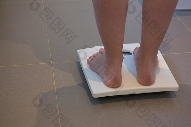 一名妇女在家里用磅秤检查<strong>体重</strong>