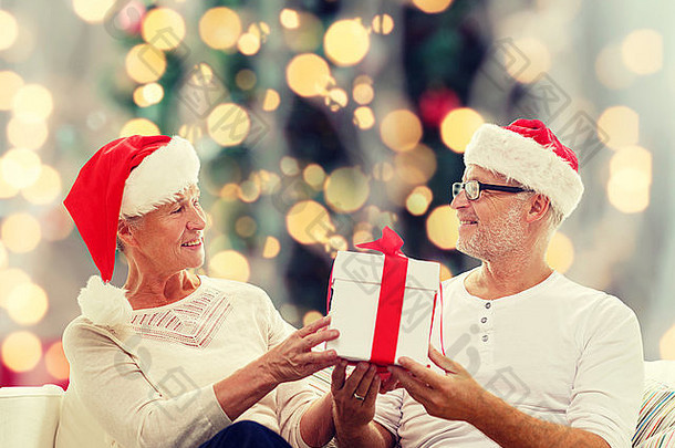 戴圣诞老人帽的快乐老年夫妇，带着礼品盒