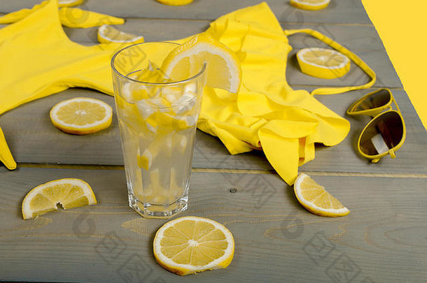 柠檬水，黄色泳装一体式，飞行员太阳镜夹在灰色木板上的柠檬部分之间。伍德海滩配件